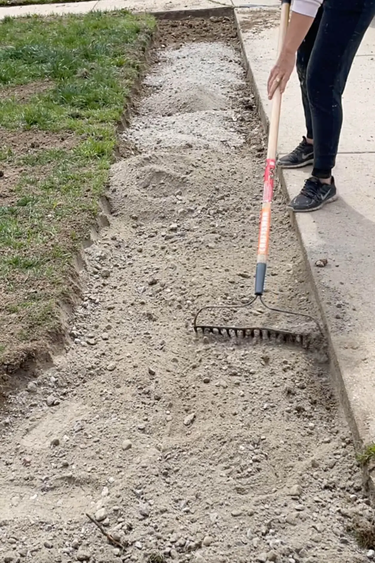 Raking road base before laying pavers for widening driveway.